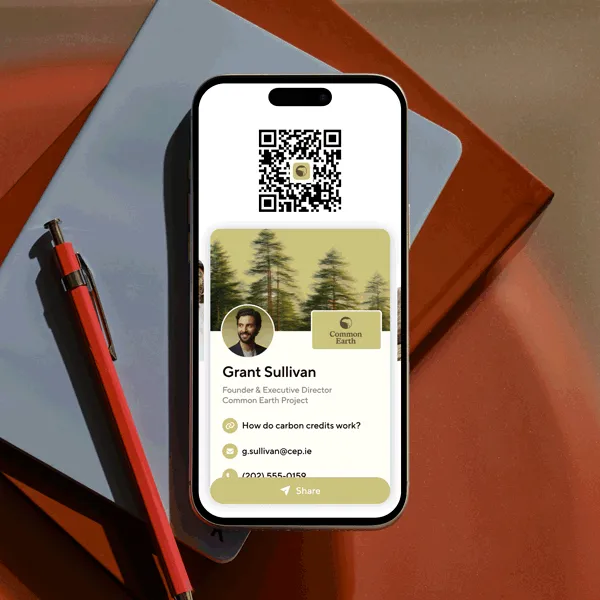 Smartphone on a desk showing a digital business card with QR code and contact details